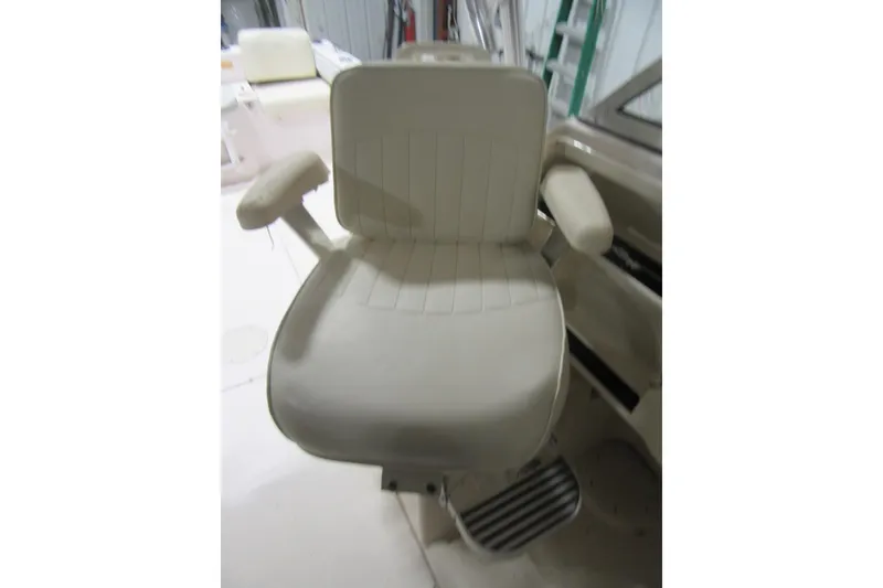 Slide: The Image of Captain's chair on 2004 Grady-White Seafarer 228 boat, featuring cushioned armrests. - 47