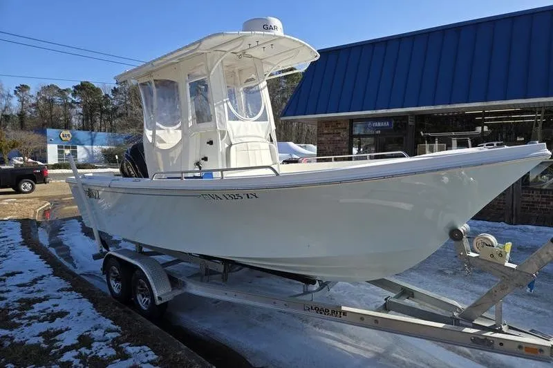Slide: The Image of 2021 Parker 2100 CC boat on trailer outside a blue-roofed building. - 2