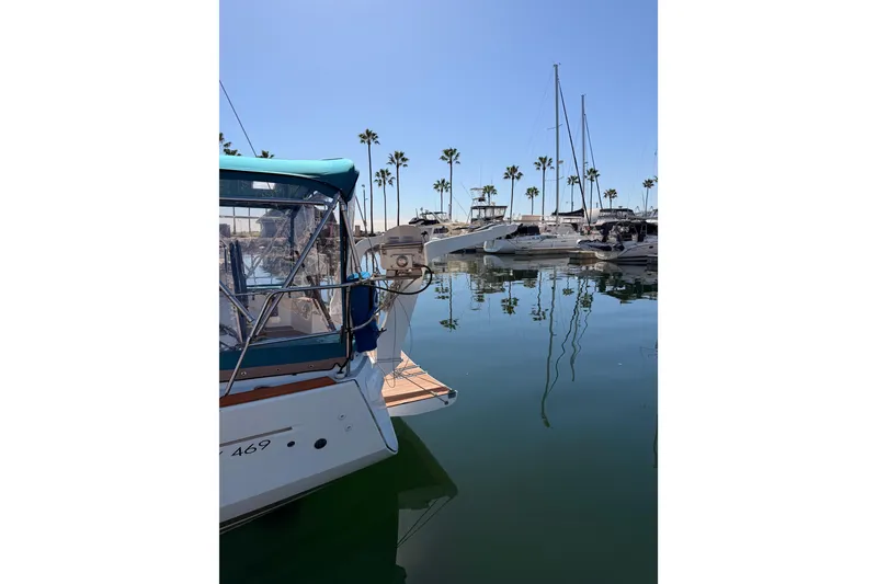 Slide: The Image of 2014 Jeanneau Sun Odyssey 469 docked in a marina with palm trees and clear blue sky. - 2