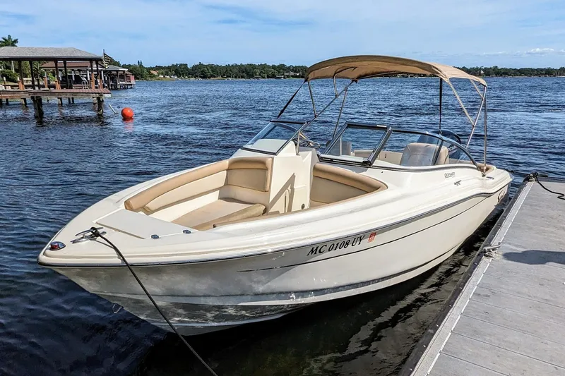 Slide: The Image of 2022 Scout 210 Dorado boat docked on a calm lake with a canopy. - 3