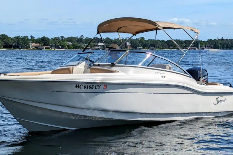 Slide: The Image of 2022 Scout 210 Dorado boat on a lake with a tan canopy. - 4