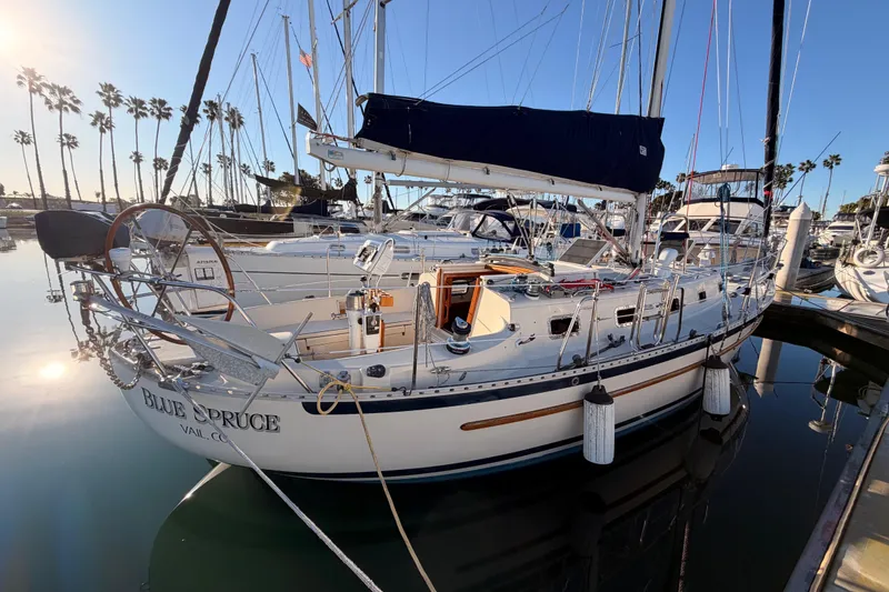 Slide: The Image of Sailboat docked in marina, 1995 Pacific Seacraft 34, named "Blue Spruce," with palm trees in background. - 2