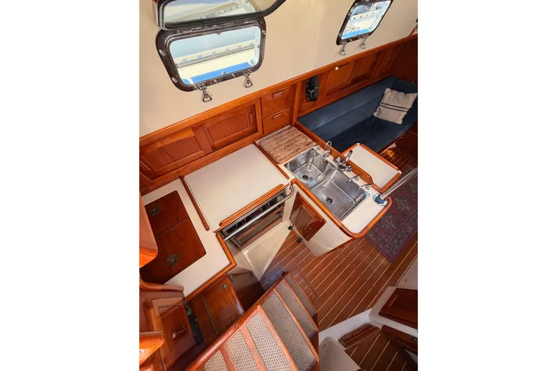 Slide: The Image of Interior of 1995 Pacific Seacraft 34 sailboat, featuring a compact kitchen and wooden cabinetry. - 39