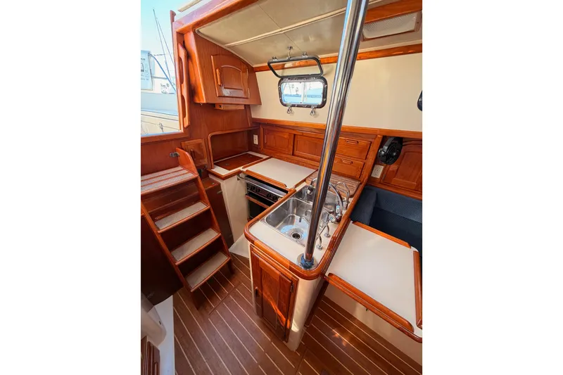 Slide: The Image of Interior of 1995 Pacific Seacraft 34 sailboat, featuring a compact wooden kitchen area. - 41