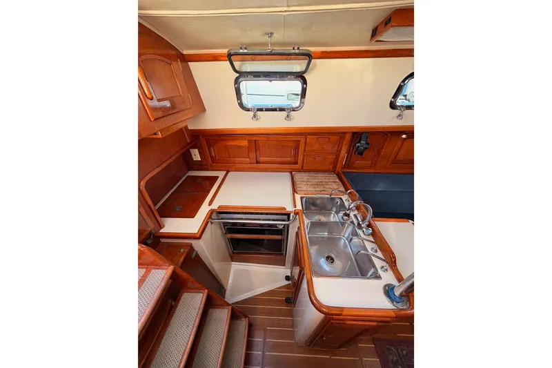 Slide: The Image of Interior of 1995 Pacific Seacraft 34 sailboat, featuring a compact kitchen with wooden cabinetry. - 42