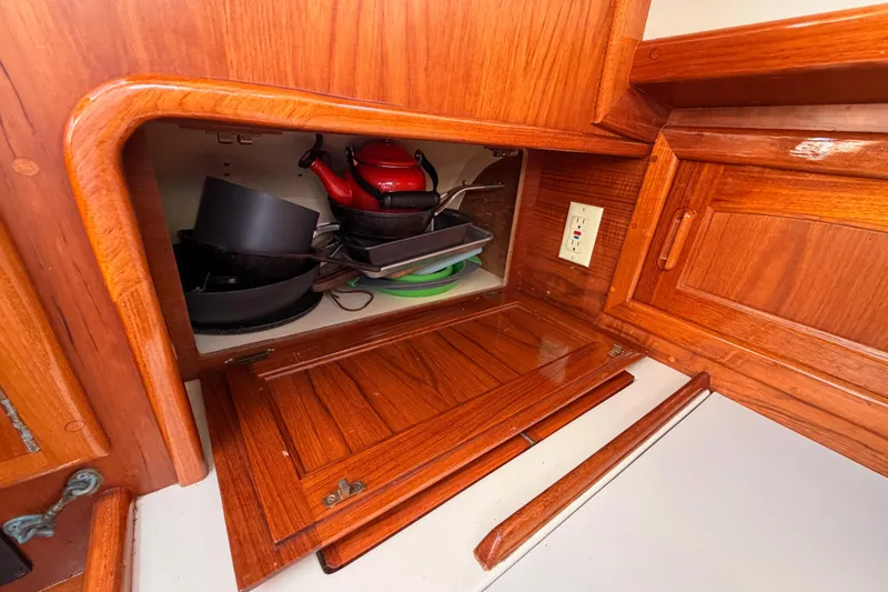Slide: The Image of Wooden cabinet with cookware inside, aboard a 1995 Pacific Seacraft 34 sailboat. - 44