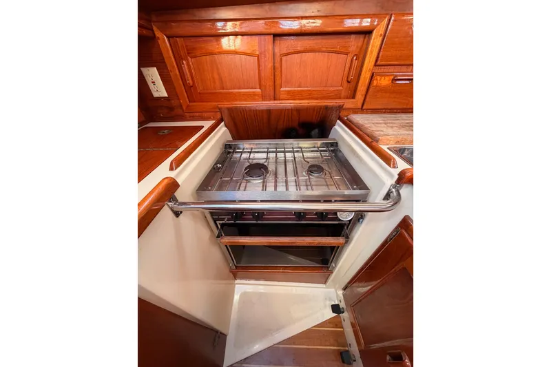 Slide: The Image of 1995 Pacific Seacraft 34 yacht kitchen with stove and wooden cabinetry. - 45