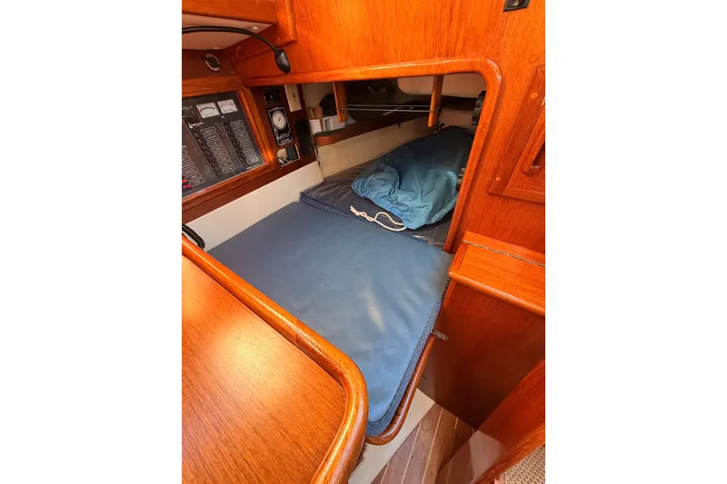 Slide: The Image of 1995 Pacific Seacraft 34 interior cabin with wooden finish and blue bedding. - 48