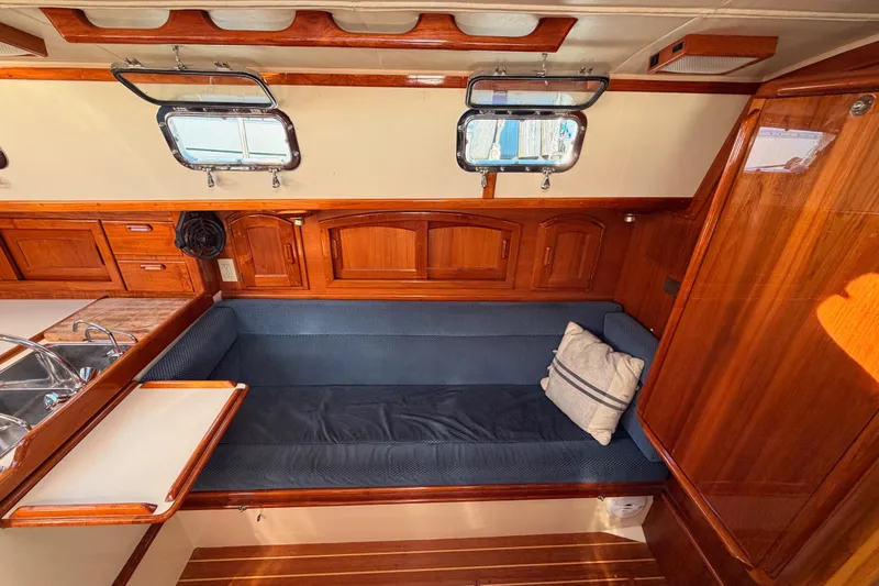 Slide: The Image of Interior of 1995 Pacific Seacraft 34 sailboat with wooden cabinetry and blue cushioned seating. - 55