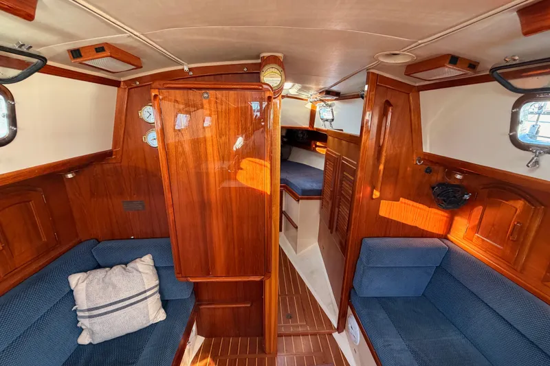 Slide: The Image of Interior of a 1995 Pacific Seacraft 34 sailboat with wooden finishes and blue seating. - 61