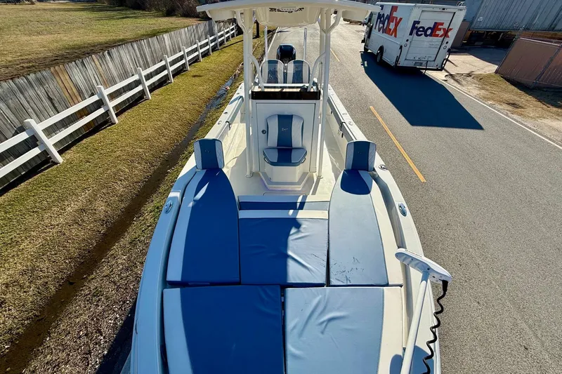 Slide: The Image of 2022 Ranger 2510 Bay boat with blue seating, parked near a road and fence. - 17