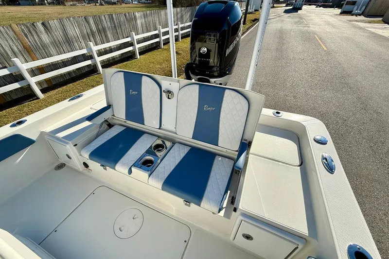 Slide: The Image of 2022 Ranger 2510 Bay boat with blue and white seating, outdoor setting. - 7