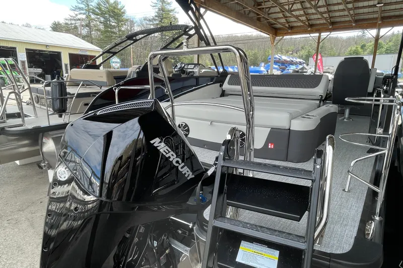 Slide: The Image of 2026 Harris Sunliner 230 pontoon boat with Mercury engine, docked under a wooden roof. - 19