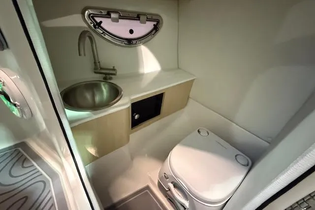 Slide: The Image of 2026 Regal LS6 Surf boat bathroom with sink, toilet, and porthole window. - 11