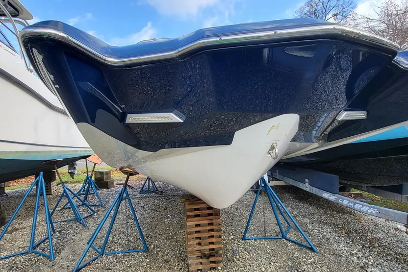 Slide: The Image of 2021 Malibu Wakesetter 23 MXZ boat hull on stands, blue and white design. - 2