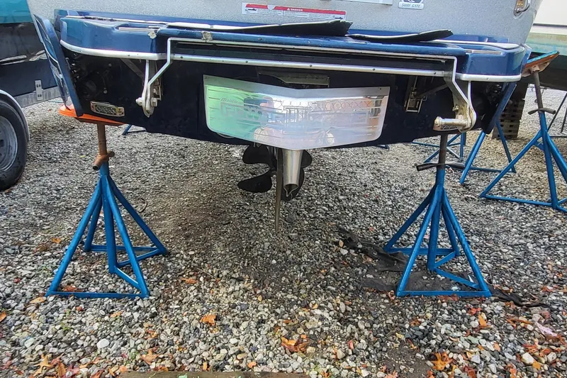 Slide: The Image of 2021 Malibu Wakesetter 23 MXZ boat on stands, rear view, gravel surface. - 7