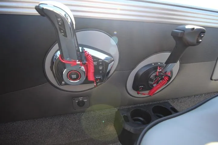Slide: The Image of 2026 Lund 2275 Baron boat controls with red safety lanyards and cup holders. - 17