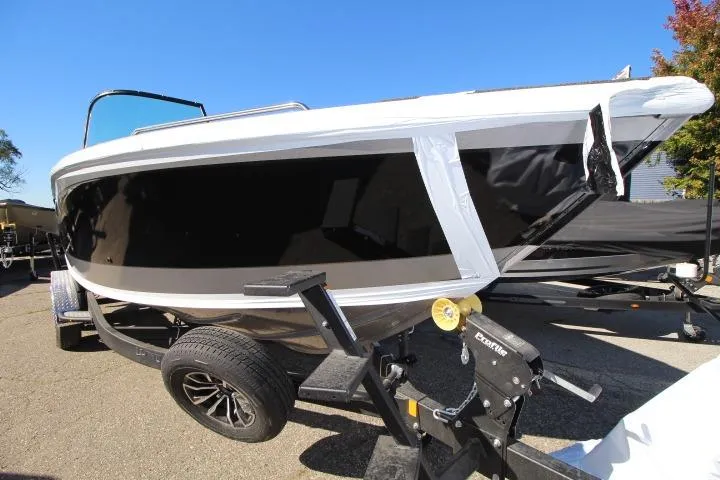 Slide: The Image of 2026 Lund 2275 Baron boat on trailer, black and white exterior, sunny day. - 19