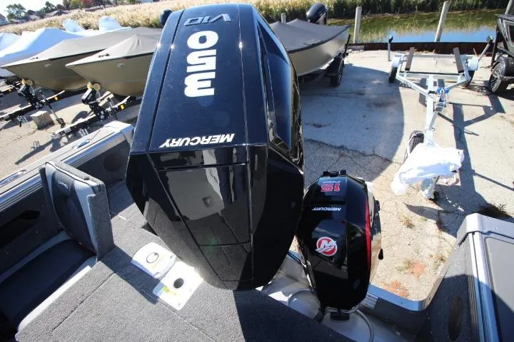 Slide: The Image of 2026 Lund 2275 Baron boat with Mercury outboard motor, docked near water. - 22