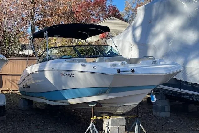 The Image of 2022 NauticStar 223 DC boat with canopy, displayed outdoors on blocks. - 0