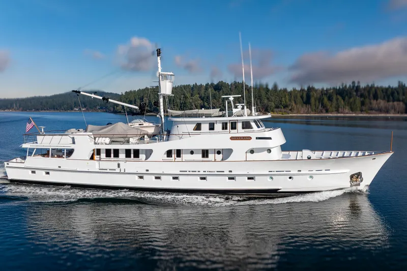 Slide: The Image of Vintage 1974 Willard 1201 yacht cruising on a serene lake with forested background. - 4