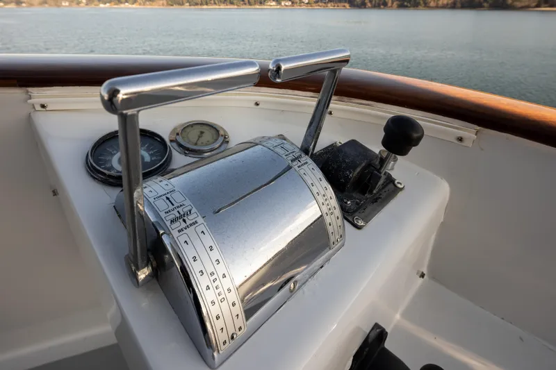Slide: The Image of 1974 Willard 1201 boat controls with throttle levers and gauges, overlooking calm water. - 49