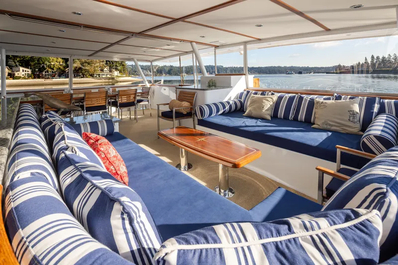 Slide: The Image of Luxurious 1974 Willard 1201 yacht interior with blue-striped seating and scenic waterfront view. - 54