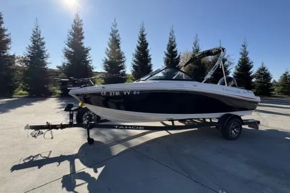 The Image of 2022 Tahoe 200 S boat on trailer, parked outdoors with trees in background. - 0