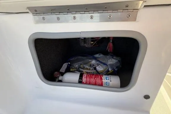 Slide: The Image of Storage compartment in a 2022 Tahoe 200 S boat with fire extinguisher and wiring. - 22
