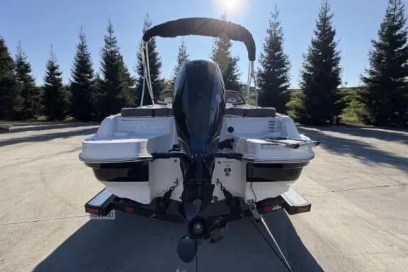 Slide: The Image of 2022 Tahoe 200 S boat, rear view, parked outdoors with trees in the background. - 6