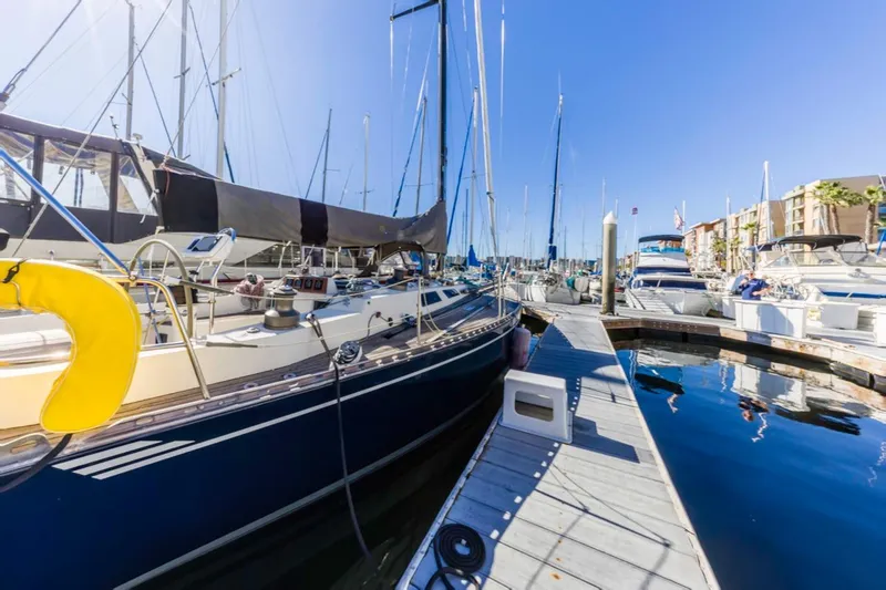 Slide: The Image of 1983 Baltic 42 DP sailboat docked at a sunny marina, surrounded by other boats. - 10