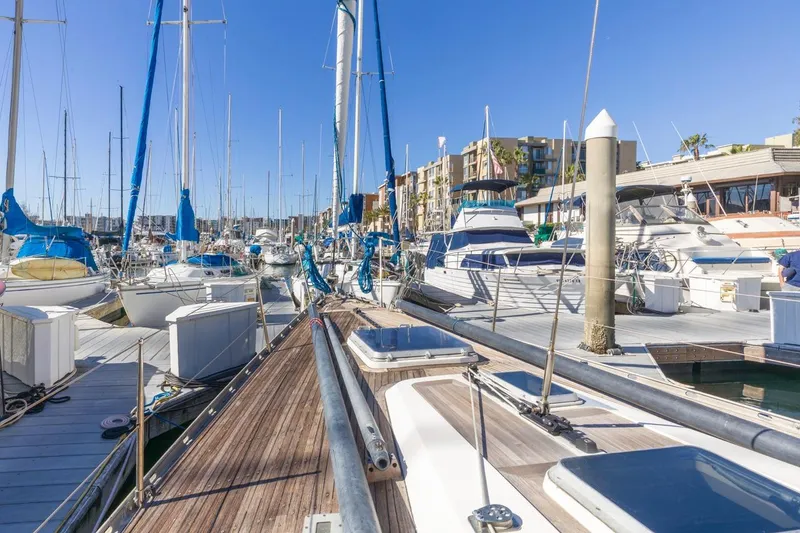 Slide: The Image of Sailboats docked at a marina, featuring a 1983 Baltic 42 DP under clear blue skies. - 18