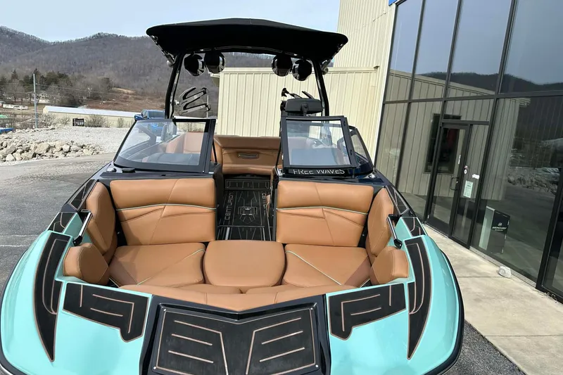 Slide: The Image of 2022 Centurion Fi23 boat with tan interior, parked near a modern building. - 7