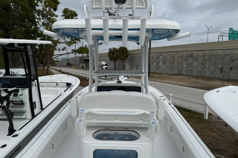 Slide: The Image of 2026 Tidewater 2500 Carolina Bay boat with T-top and rod holders, parked outdoors. - 9