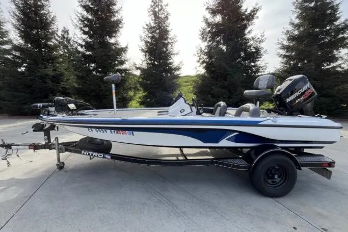 The Image of 2016 Nitro Z18 boat with trailer, parked outdoors near trees. - 1