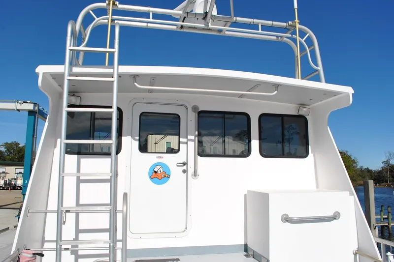 Slide: The Image of 2019 Newton 53 dive boat with ladder and cabin, docked under clear blue sky. - 6