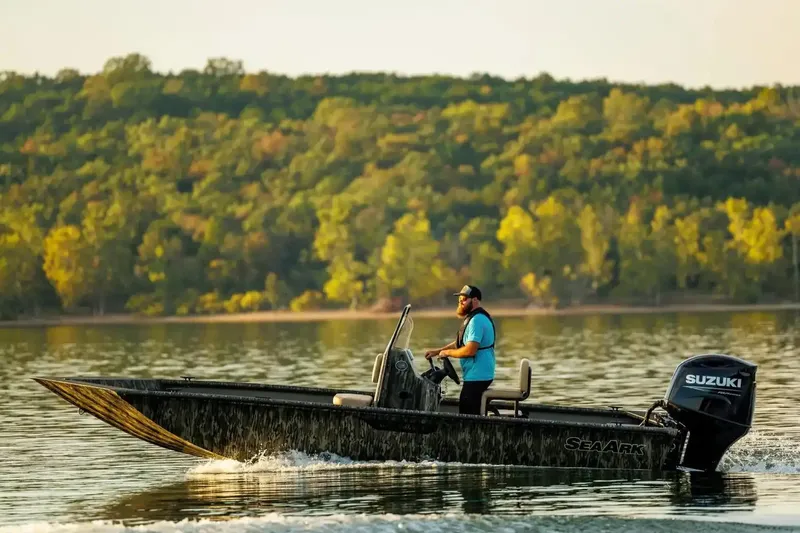 Slide: The Image of Manufacturer Provided Image: 2026 SeaArk Shadow 20T boat cruising on a serene lake with lush forest backdrop. - 10