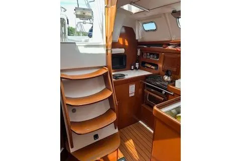 Slide: The Image of Interior of 2006 Beneteau Oceanis Clipper 393 sailboat, featuring wooden cabinetry and compact kitchen. - 16