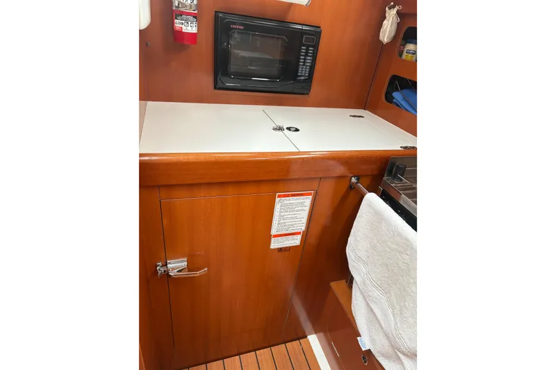 Slide: The Image of 2006 Beneteau Oceanis Clipper 393 galley with microwave, wooden cabinetry, and fire extinguisher. - 18