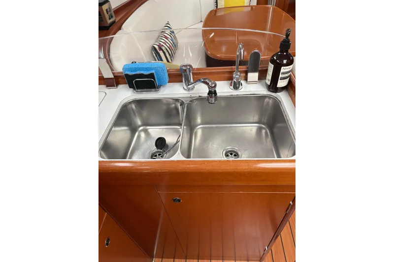 Slide: The Image of Galley sink in 2006 Beneteau Oceanis Clipper 393 yacht, featuring dual basins and wooden cabinetry. - 20
