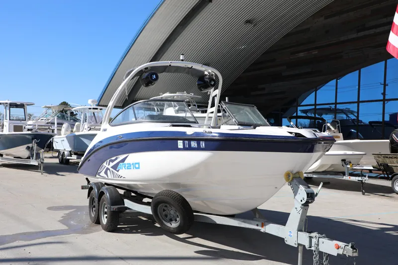 Slide: The Image of 2022 Yamaha Boats AR210 on trailer, parked outdoors near other boats. - 4