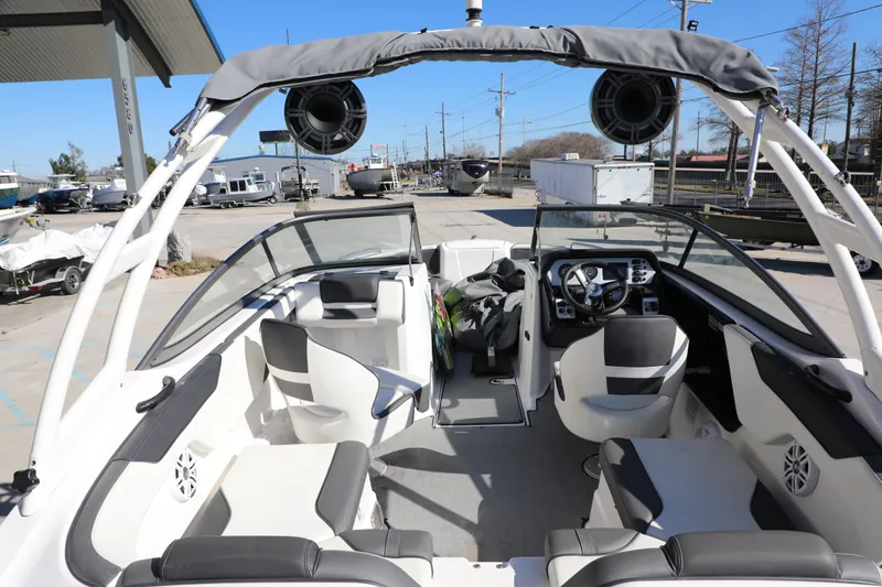 Slide: The Image of 2022 Yamaha Boats AR210 interior with seating and dashboard, parked outdoors. - 9