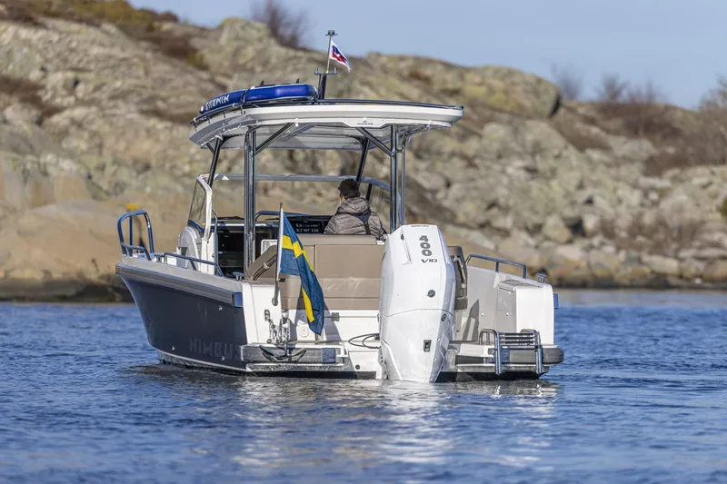 Slide: The Image of Nimbus Tender 9 boat 2025 on calm water near rocky shore. - 7