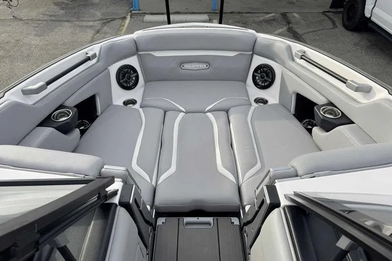Slide: The Image of 2022 Supra SL boat interior with gray seating, cup holders, and speakers. - 13