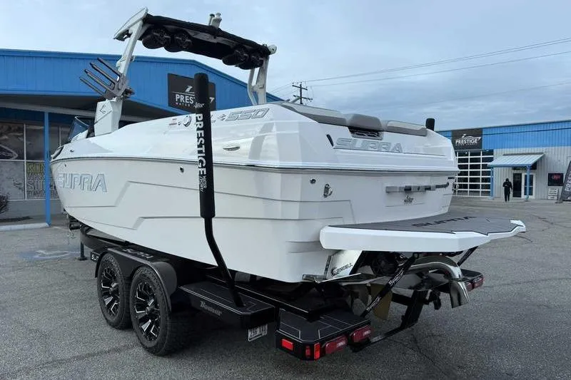 Slide: The Image of 2022 Supra SL boat on trailer, parked outside a blue building. - 3