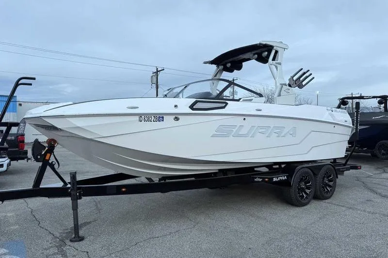 Slide: The Image of 2022 Supra SL boat on trailer, white exterior, parked outdoors. - 6