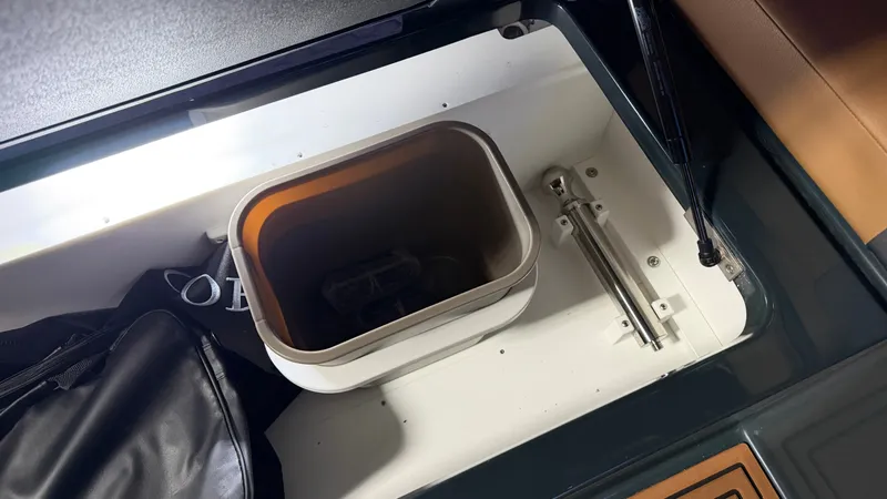 Slide: The Image of An open storage compartment with a trash bin and a black backpack. - 39