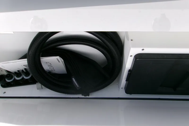 Slide: The Image of Storage compartment in 2026 Sportsman Heritage 321 Center Console boat, featuring coiled hose and manuals. - 20