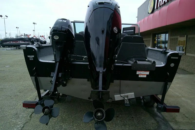 Slide: The Image of 2016 Lund 1775 Impact Sport boat with dual outboard motors, parked outside a dealership. - 6