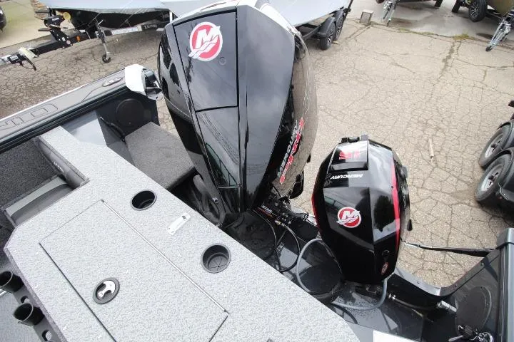 Slide: The Image of 2026 Lund 2075 Fisherman boat with dual Mercury outboard motors, docked on pavement. - 13